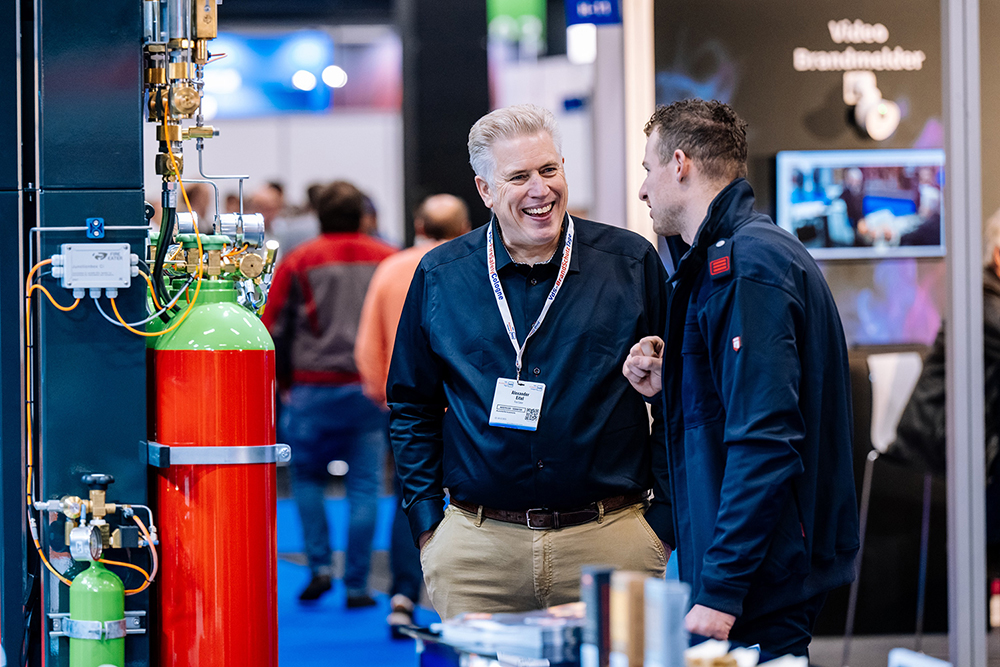 Ein Aussteller-Vertreter und ein Besucher reden am Messestand miteinander.