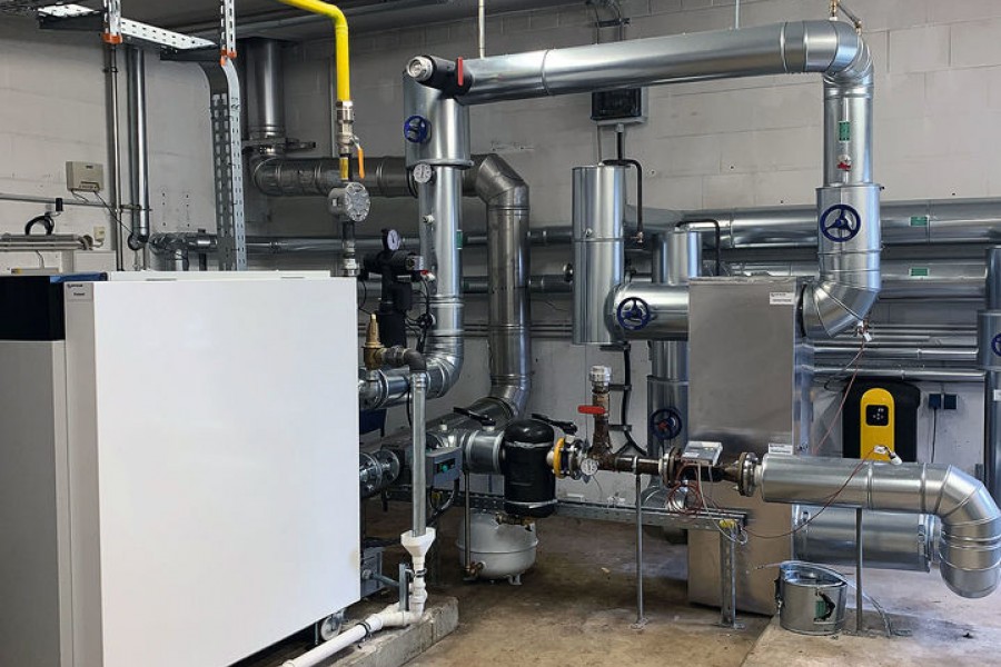 Die Heizzentrale für einen Wohnkomplex mit dem Schlammabscheider (mit schwarzer Dämmschale in der Mitte) und dem Vakuumentgaser (rechts mit schwarzgelber Hülle). Bild: Spirotech BV, Helmond/Düsseldorf